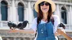 威尼斯意大利7月肖像快乐女人旅游持有鸽子喂养玩有趣的广场三马可马克的教堂夏天一天