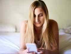 好早....社会媒体美丽的年轻的女人智能手机放松床上