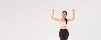 完整的长度快乐的漂亮的健身教练女运动员运动服装显示健身房促销提供可爱的浅黑肤色的女人亚洲女运动员邀请锻炼指出手指标志
