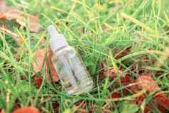 瓶血清色彩斑斓的绿色草黄色的秋天叶子背景美丽的秋天树叶自然有机化妆品产品化妆品美概念