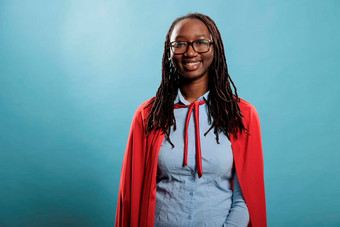 年轻的迷人的美丽的微笑非洲美国超级英雄女人穿红色的角蓝色的背景