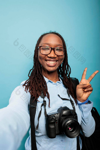 快乐微笑摄影师现代相机设备给和平标志采取自拍