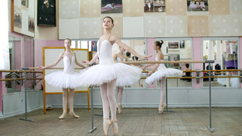 芭蕾舞大厅女孩白色芭蕾舞裙子订婚了芭蕾舞排练把年轻的芭蕾舞 演员站脚趾尖端鞋子优雅栏杆芭蕾舞大厅