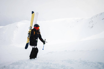 年轻的女人滑雪设备棒攀爬雪山边远地区多雾的天空雪山背景