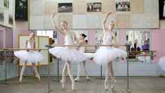 芭蕾舞大厅女孩白色芭蕾舞tutus包订婚了芭蕾舞排练相交。向前年轻的芭蕾舞 演员站脚趾尖端鞋子栏杆芭蕾舞大厅