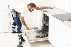 年轻的修理工服务工人修复洗碗机设备厨房