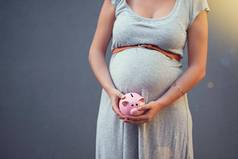 储蓄特殊的交付怀孕了女人持有存钱罐灰色的背景