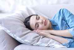 年轻的女人睡觉休息关闭眼睛沙发枕头手折叠头