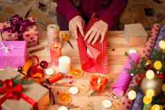 手女人黑暗红色的毛衣包装圣诞节现在木桌子上