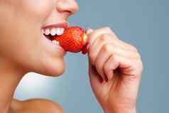 宏视图漂亮的年轻的女吃新鲜的草莓宏视图漂亮的年轻的女人吃新鲜的草莓