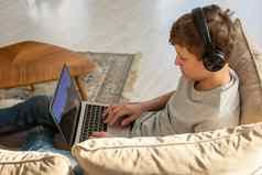 十几岁的坐在沙发房间穿黑色的耳机头戏剧电脑游戏移动PC