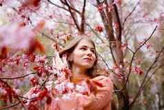 美丽的女人站粉红色的开花树春天公园