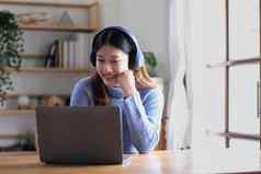 快乐的美丽的亚洲女人穿耳机数字平板电脑视频调用会议研究在线互联网