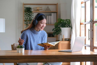 微笑年轻的亚洲青少年女孩穿耳机视频调用移动PC快乐漂亮的女人学生电脑屏幕看<strong>网</strong>络研讨会视频闲谈，聊<strong>天网</strong>络摄像头