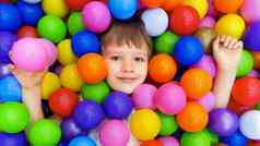 微笑孩子说谎色彩斑斓的塑料球池色彩斑斓的球干池幼儿园操场上孩子室内玩区域游戏室孩子们球坑高加索人男孩室内操场上孩子们玩区孩子们区