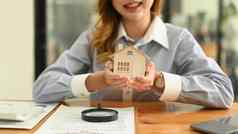 快乐年轻的女人投资者持有微型房子手真正的房地产投资购买出售概念