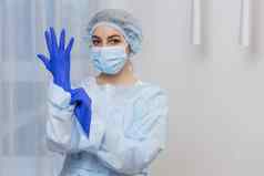 年轻的女医生准备手术穿蓝色的外科手术手套白色外套面具相机