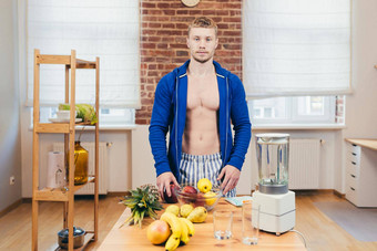 肖像年轻的英俊的泵肌肉发达的体育男人。站厨房表格首页切割苹果水果健康的健康的食物相机微笑