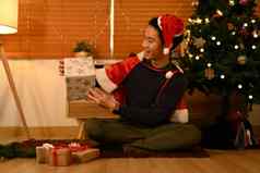 兴奋男人。穿圣诞老人他坐着装饰圣诞节树开放礼物假期圣诞节概念