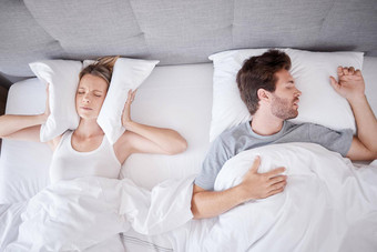 睡觉打鼾妻子枕头耳朵停止噪音丈夫床上睡眠问题失眠挫折压力累了女人卧室说谎男人。呼吸暂停