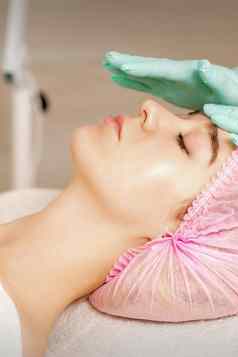 女人化妆品治疗美容师医疗手套触碰女脸水疗中心沙龙