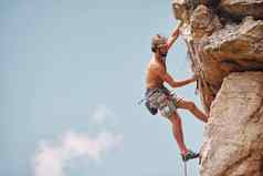 男人。山岩石攀爬悬崖挂肾上腺素运动员冒险检查安全设备钩绳子无所畏惧的男人。健身锻炼锻炼极端的体育运动