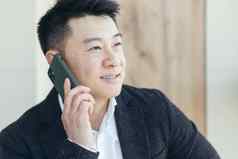 亚洲商人特写镜头肖像成功的快乐微笑会说话的电话业务西装