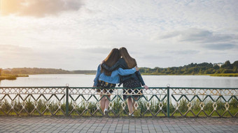 女朋友坐着拥抱湖海岸