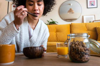非洲美国女人吃格兰诺拉<strong>麦片</strong>早餐<strong>首页</strong>生活房间咖啡橙色汁复制空间