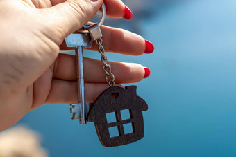 键钥匙链形状房子女手背景海概念购买房子公寓真正的房地产年轻的家庭抵押贷款贷款租赁住房