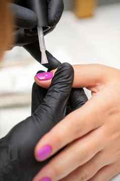 绘画指甲女人手指甲修饰师黑色的手套应用粉红色的指甲波兰的女指甲美沙龙