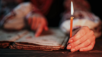 乌克兰女人阅读古老的书圣经集中用心手指纸页面蜡烛光历史基辅休息诗篇世纪祈祷诗篇