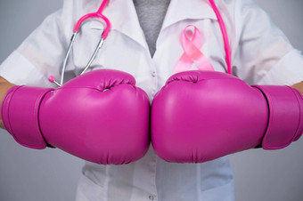 不知名的女医生<strong>粉</strong>红色的拳击手套<strong>粉</strong>红色的丝带灰色的背景战斗乳房癌症