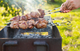 烹饪希什烤肉串烧烤烟男人。翻转串新鲜的肉烧烤烤火野餐自然