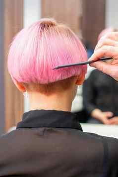 专业理发师刷牙短粉红色的头发年轻的女人梳子美容沙龙女人头发后视镜复制空间回来视图
