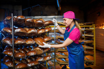专业贝克年轻的漂亮的女人牛仔裤围裙持有新鲜的面包背景面包店面包店面包店产品面包生产