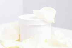 白色Jar奶油精致的白色玫瑰花花瓣光背景自然有机化妆品概念关闭模型