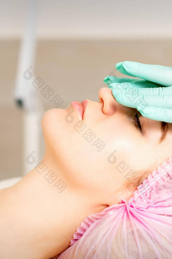 美容师戴着手套手适用于保湿面具剥奶油女脸<strong>面部</strong>美容治疗程序<strong>面部</strong>护理