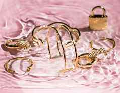 金手镯耳环环Jewelery粉红色的水背景奢侈品魅力假期美设计珠宝品牌广告