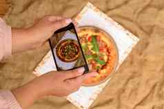 拍摄食物手采取图片美味的披萨智能手机