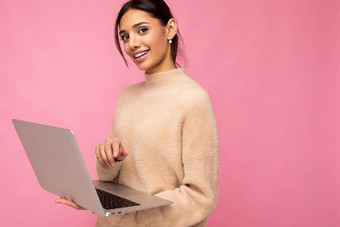 肖像拍摄美丽的可爱的迷人的积极的快乐的可爱的微笑年轻的浅黑肤色的女人女人休闲<strong>米色</strong>毛衣孤立的粉红色的背景复制空间在移动PC电脑教育自由概念