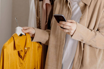 女人持有智能手机采取照片衣服出售在线销售网站电子商务重用二手概念有意识的消费者可持续发展的生活方式特写镜头视图