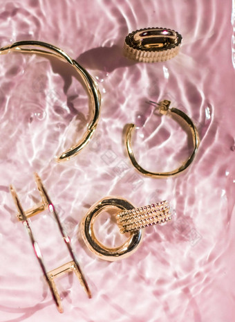 金手镯耳环环Jewelery粉红色的水背景奢侈品魅力假期美设计珠宝品牌广告