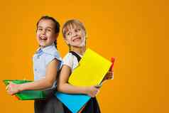 教育概念集肖像多样化的小学生持有堆栈学术书穿背包黄色的橙色颜色工作室背景