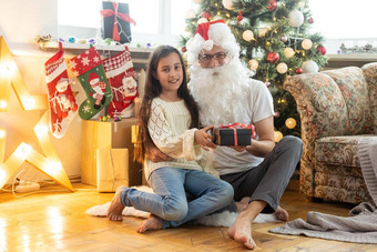 图片快乐家庭庆祝一年夏娃女孩父母享受冬天假期父亲穿圣诞老人老人服装圣诞节魔法幸福爱概念