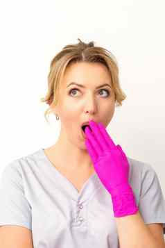 肖像年轻的女高加索人医生护士震惊了覆盖口粉红色的戴着手套手白色背景
