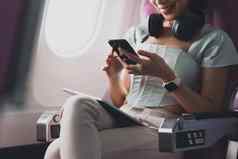 年轻的亚洲女人智能手机连接无线网络互联网飞行董事会旅行概念