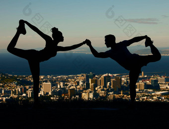 轮廓夫妇伸展运动瑜伽日出城市男人。女人培训锻炼锻炼日落人持有手瑜伽构成城市背景