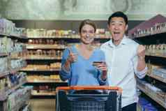 家庭购物年轻的美丽的跨种族夫妇购物超市信贷卡