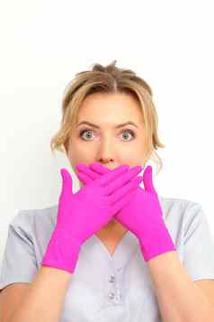 肖像年轻的女高加索人医生护士震惊了覆盖口粉红色的戴着手套手白色背景